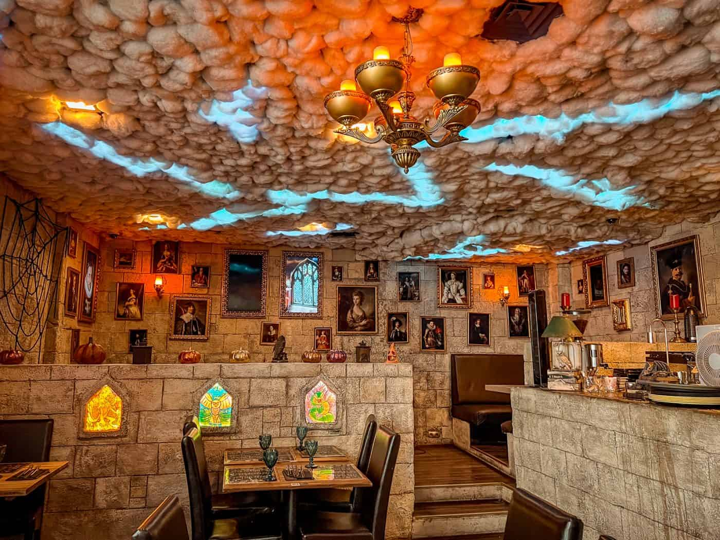 Magischer Restaurantbereich mit leuchtender Wolkendecke und Porträts